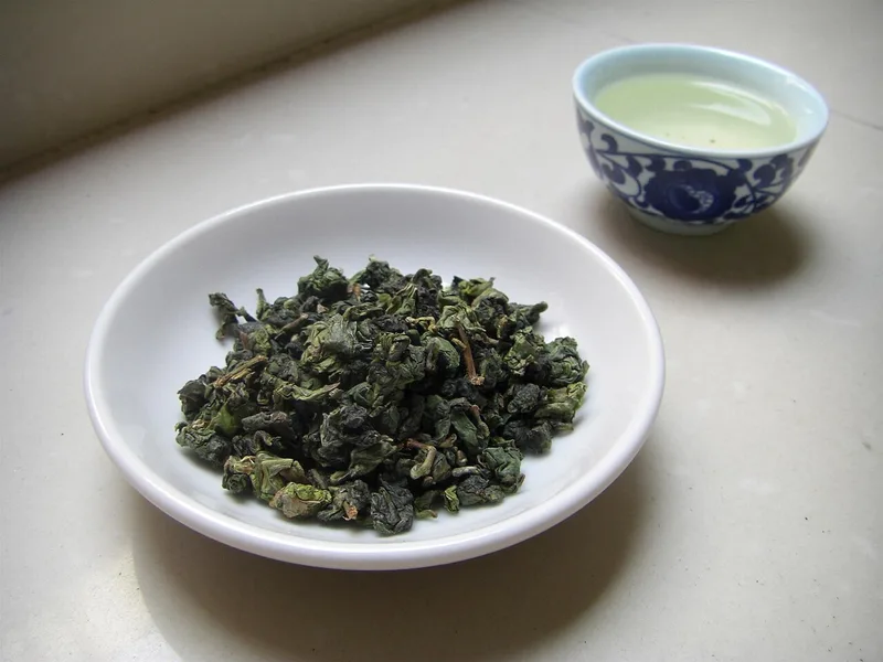 Tieguanyin leaves beside a cup of tea